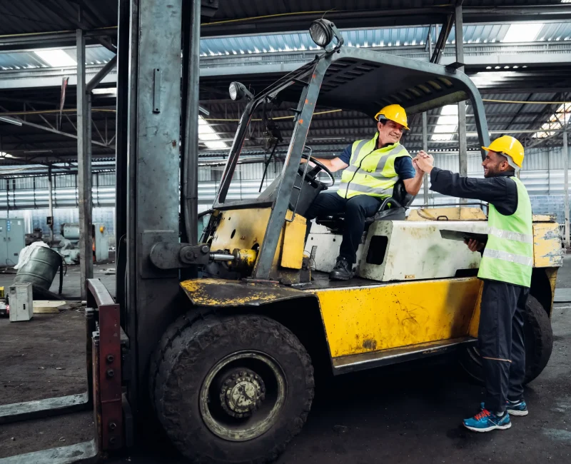 two-men-are-standing-next-to-a-forklift-one-of-th-2024-04-30-17-21-41-utc